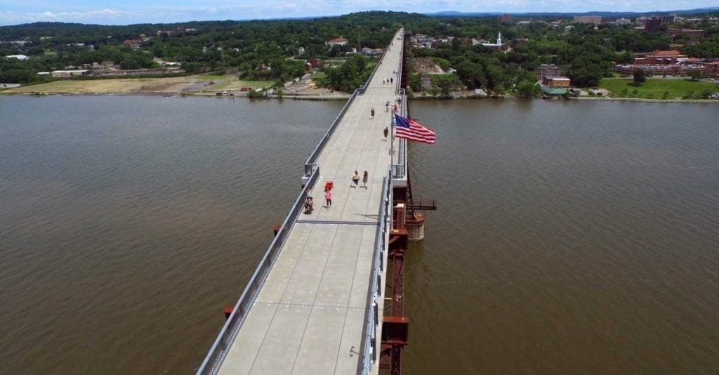 A bridge with people walking across it and an american flag on the top.