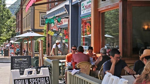 A group of people sitting at tables outside.