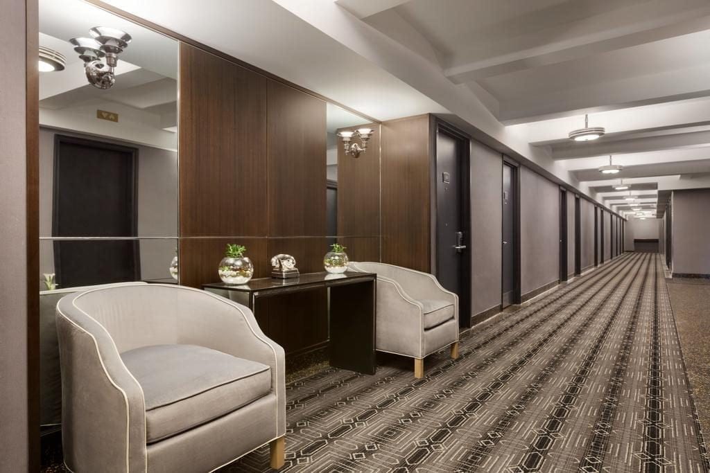 A hotel room with two chairs and a desk.