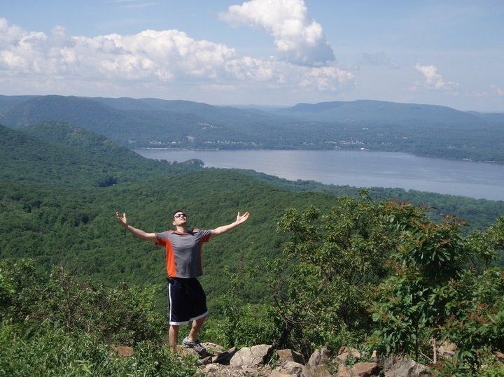 A man standing on top of a mountain with his arms in the air.