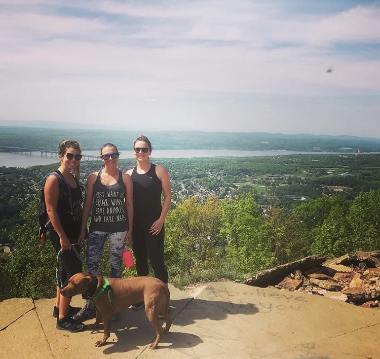 Three people and a dog standing on top of a hill.