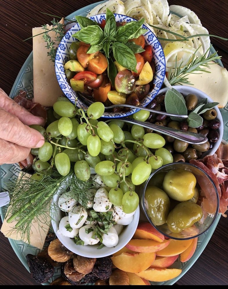 A platter of food with grapes, olives and other vegetables.