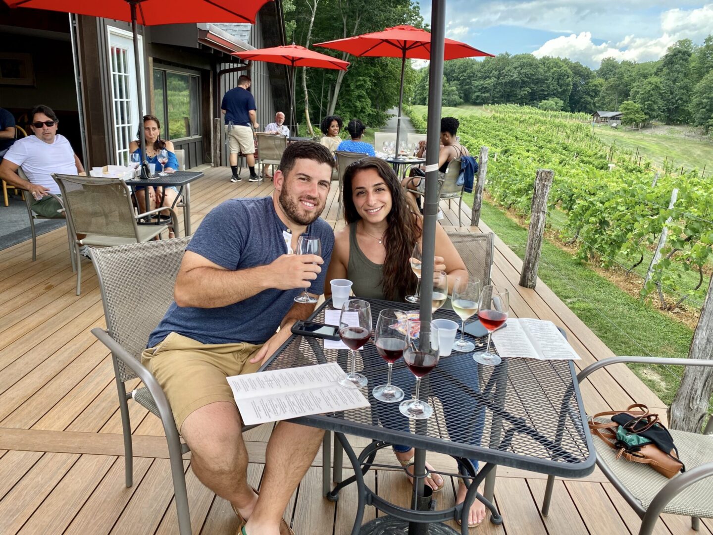 A man and woman sitting at an outdoor table with wine glasses.