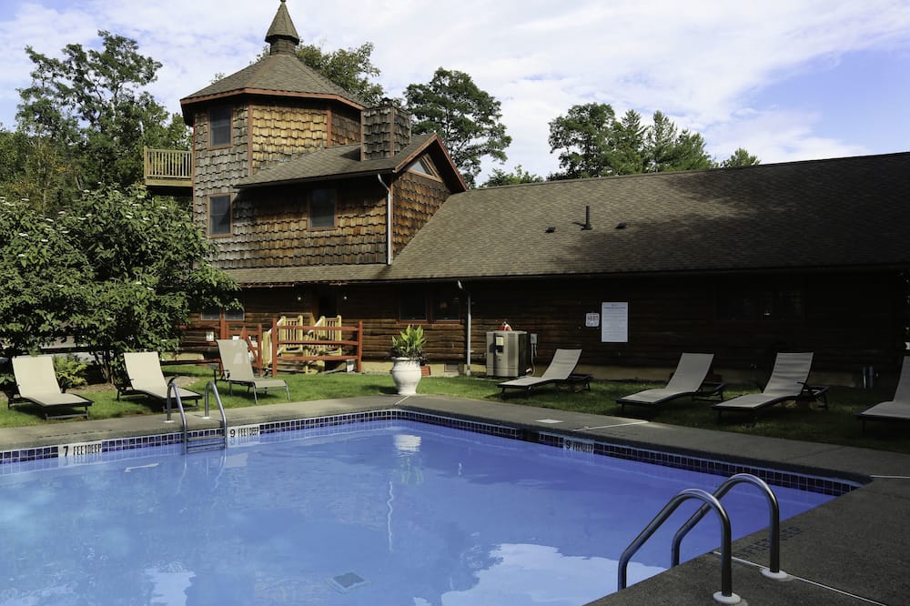 A pool with chairs and a house in the background.