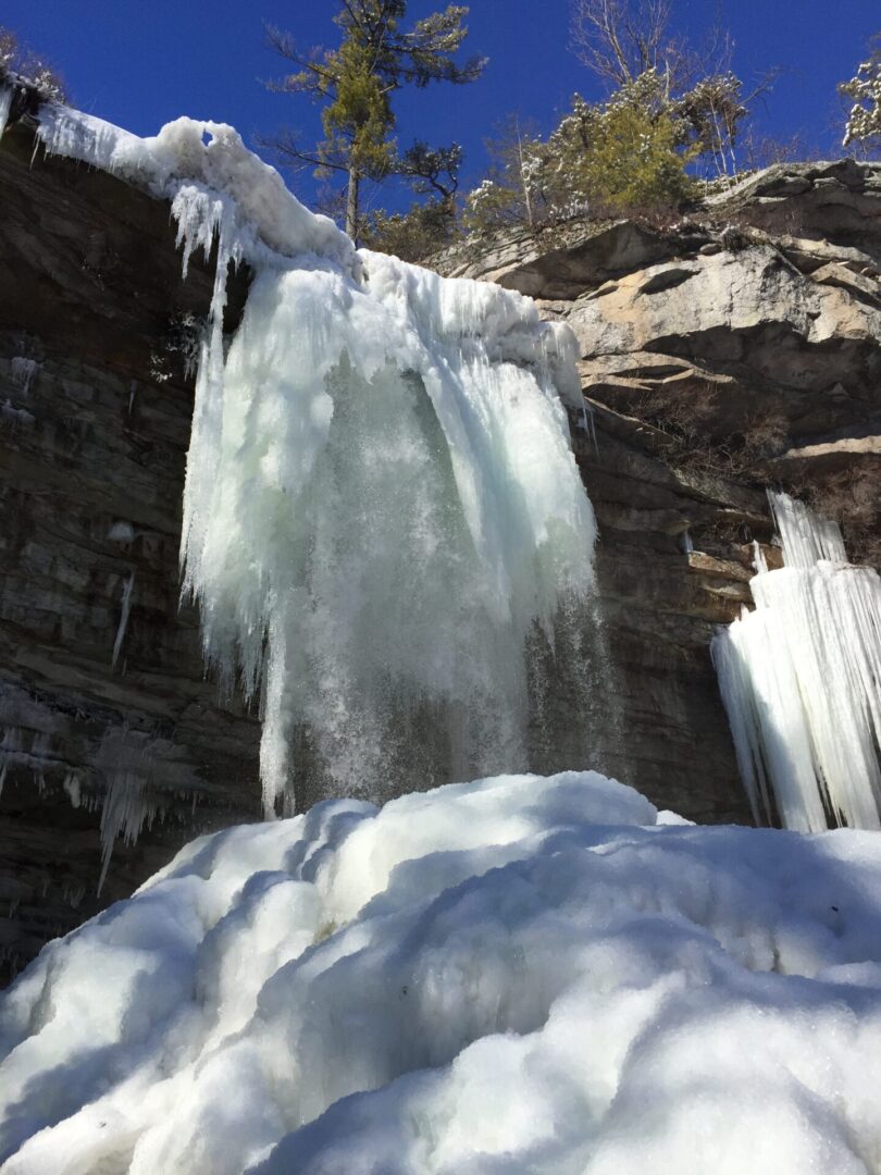A waterfall with snow on the ground and rocks