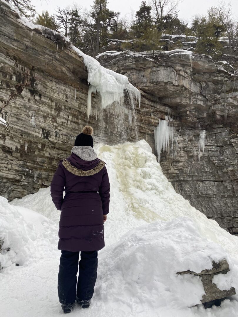 A person standing in the snow near some ice