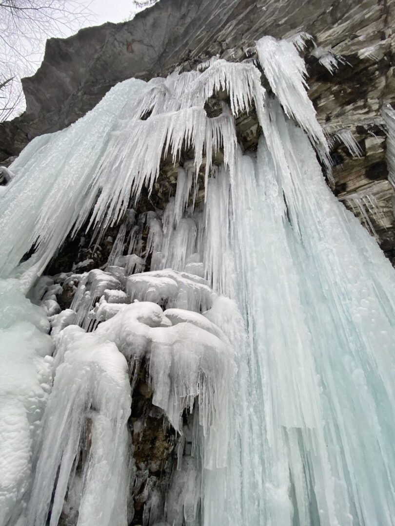A waterfall with lots of icicles hanging from it's side.