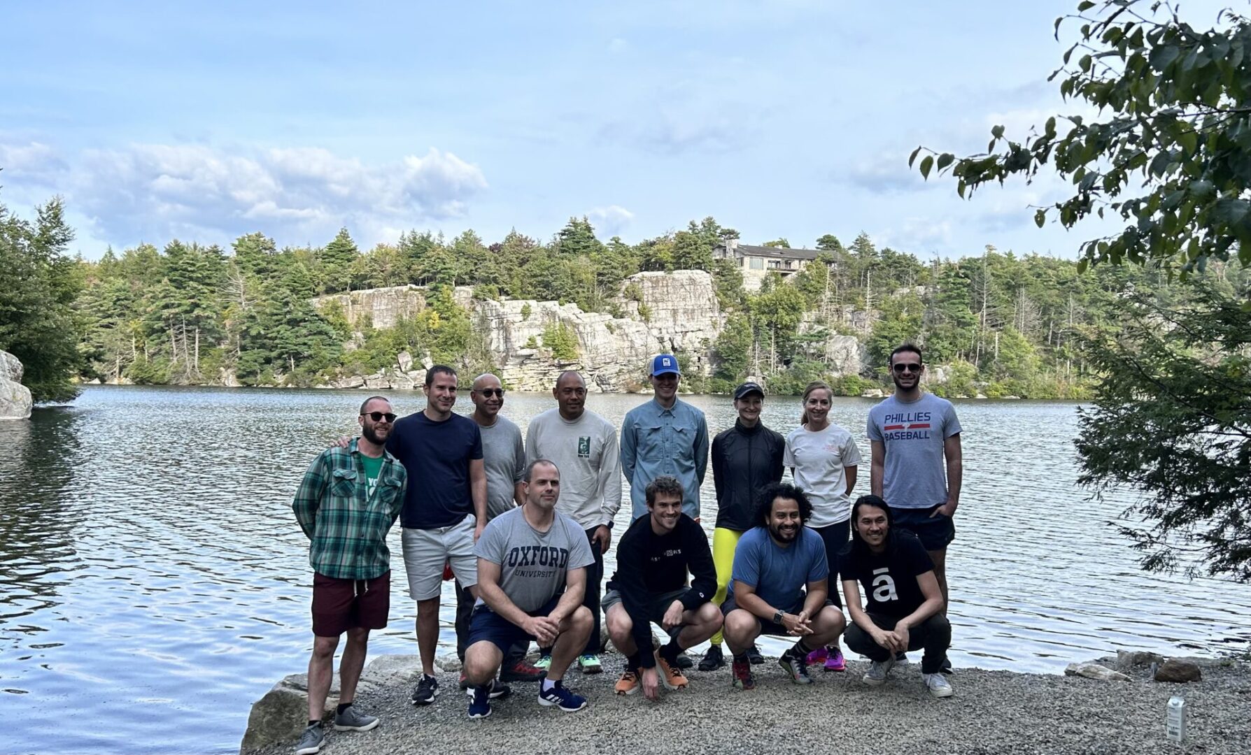 A group of men standing on top of a rock near water.