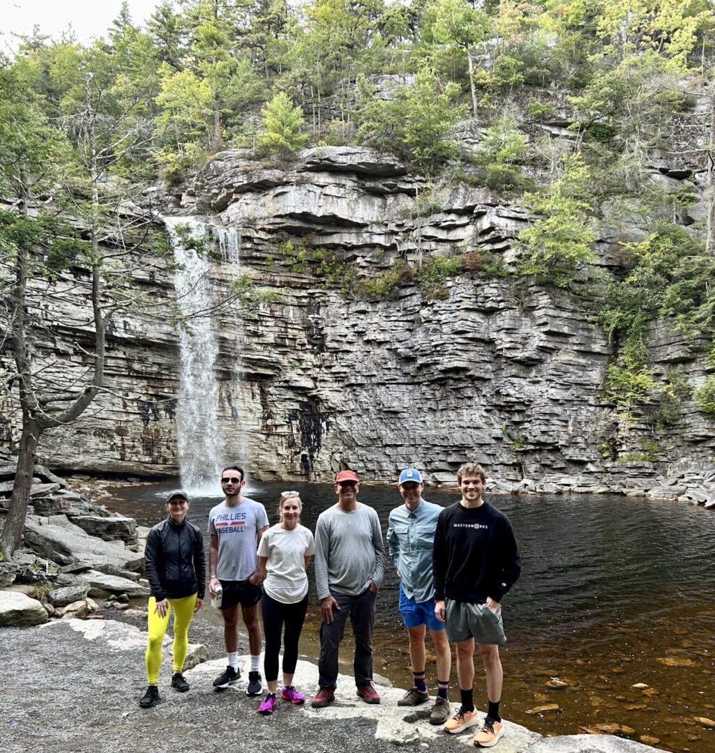 A group of people standing in front of a waterfall.