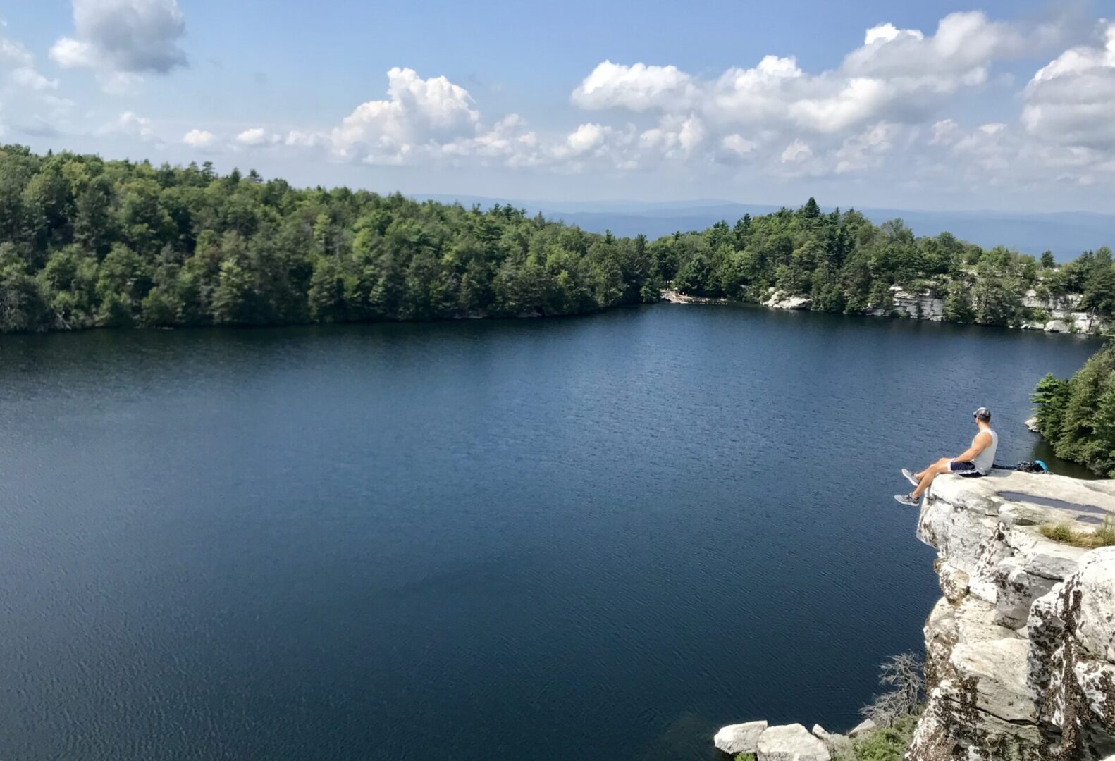 A lake with trees in the background and clouds above.