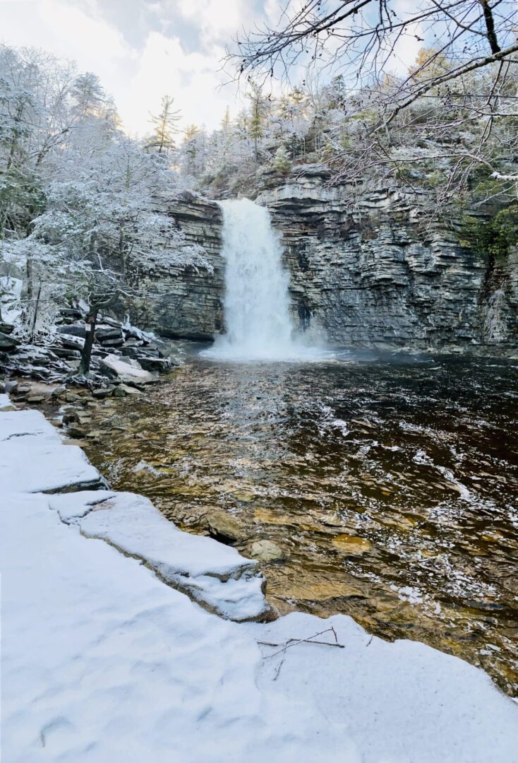 A waterfall is shown in the snow.