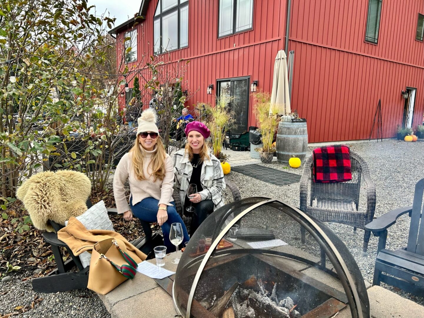 Two women sitting in front of a fire pit.