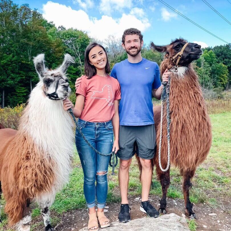 A man and woman standing next to two goats.