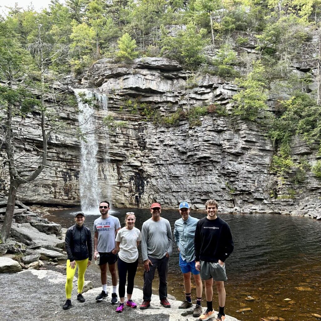 A group of people standing in front of a waterfall.