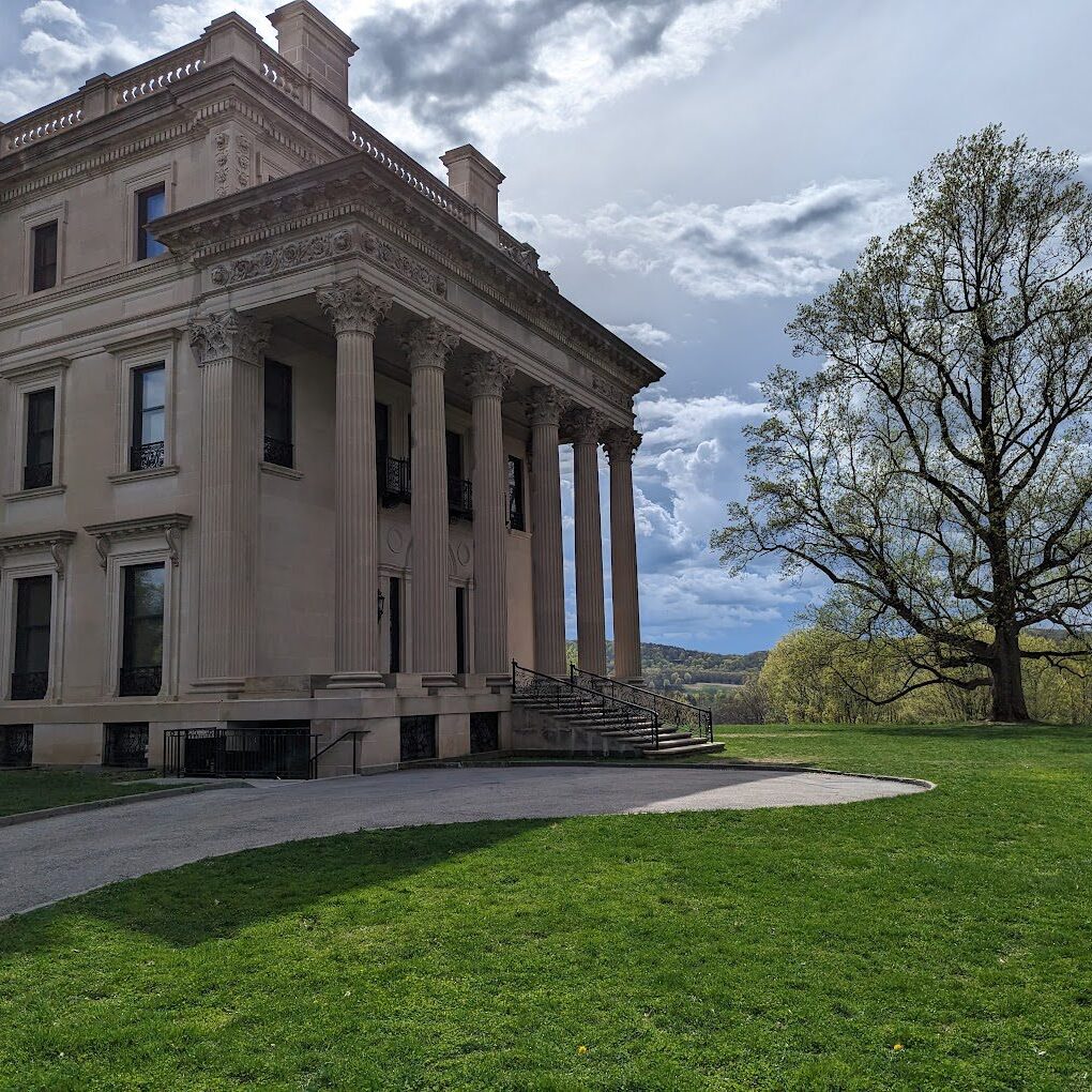 A large building with pillars and a tree in the background.