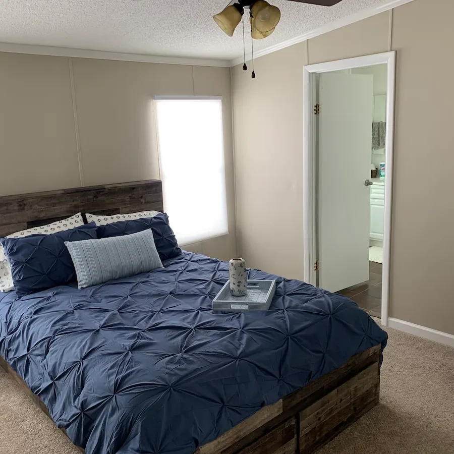 A bedroom with a bed, mirror and window.